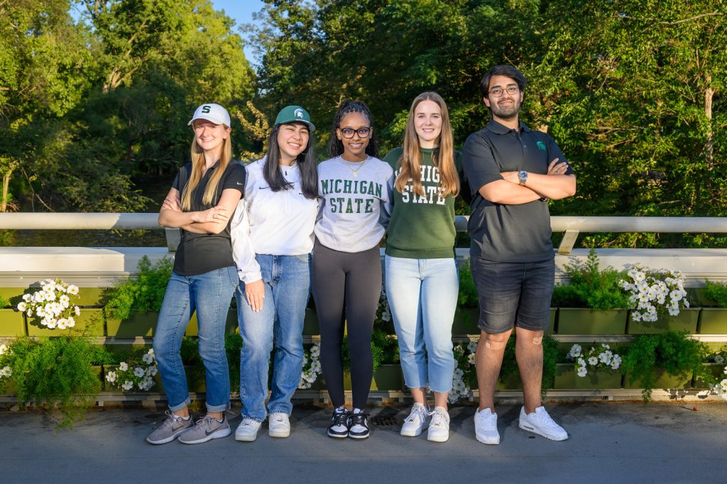 Five members of the 2023 MSU Homecoming Court pose on a bridge on campus.