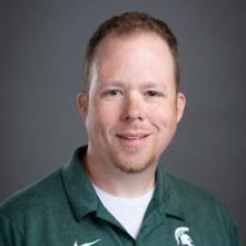 Headshot of man wearing a green polo with a MSU Spartan logo on chest.