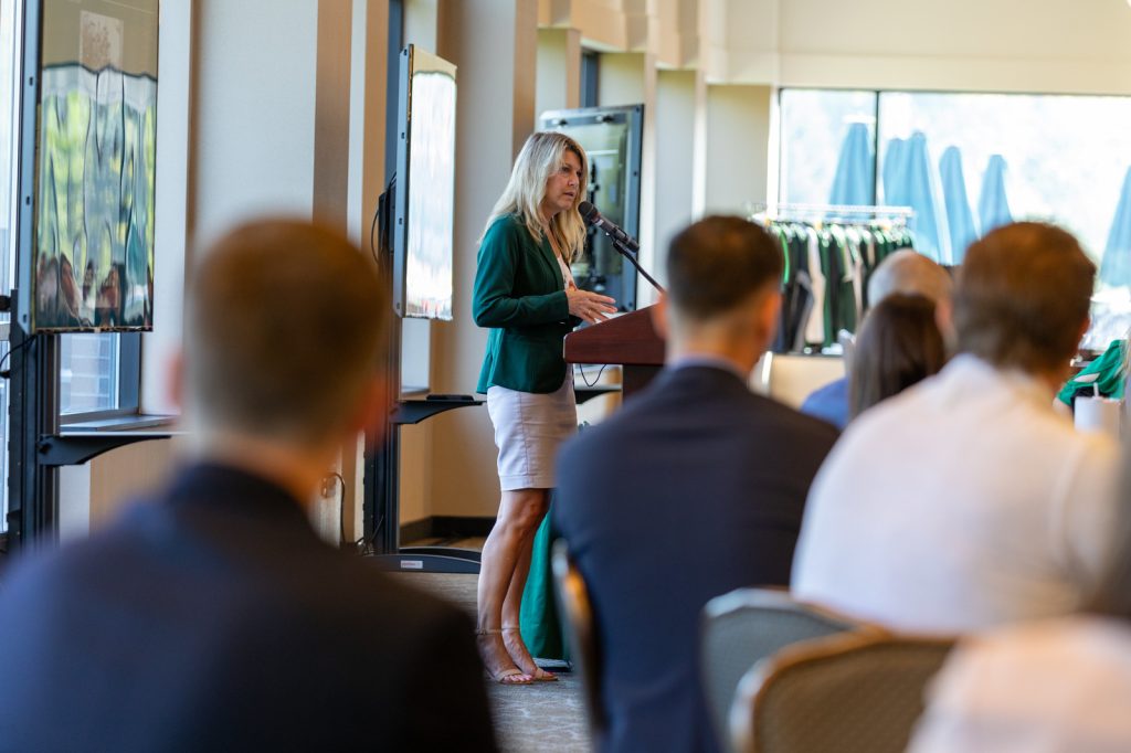 Cheri DeClercq speaking from a podium to welcome the Executive MBA Class of 2025.