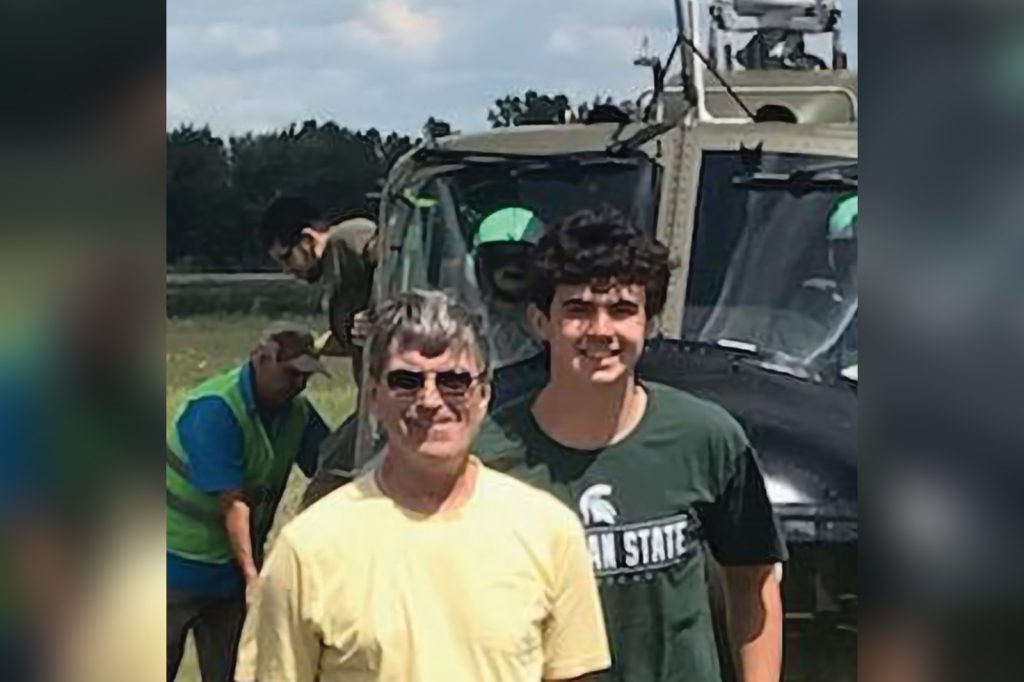 Jacob Weber and his grandpa pose near a military helicopter.