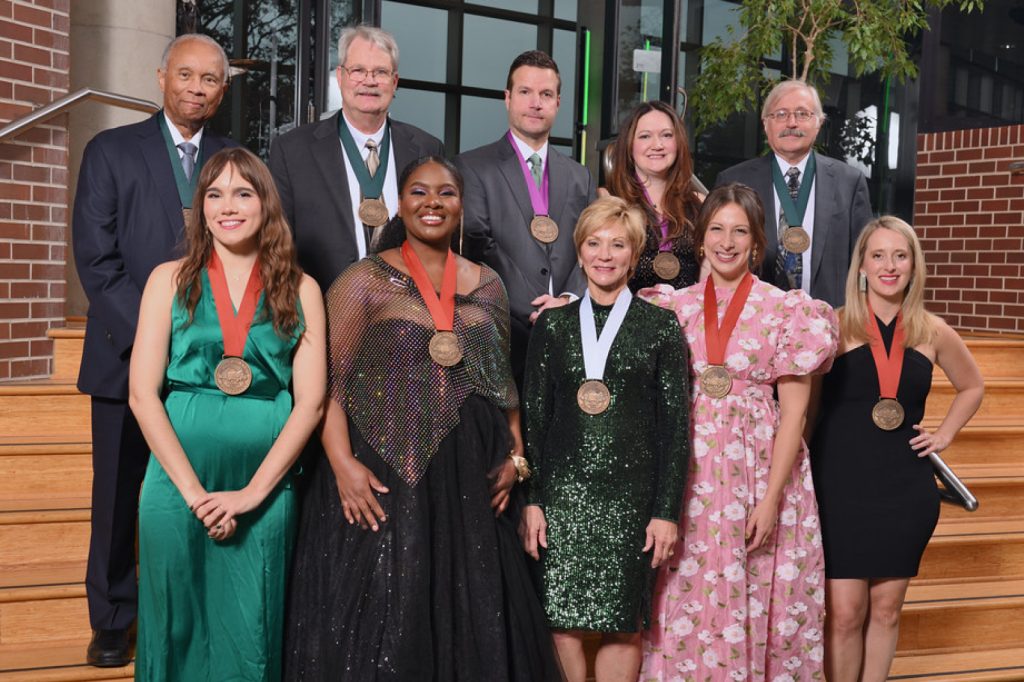 2023 Alumni Grand Award recipients, nine people standing in formal wear with medals around their necks