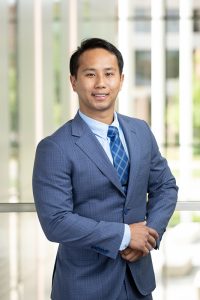 portrait of Jordan Fu, male presenting adult with black hair in a blue suit and tie.