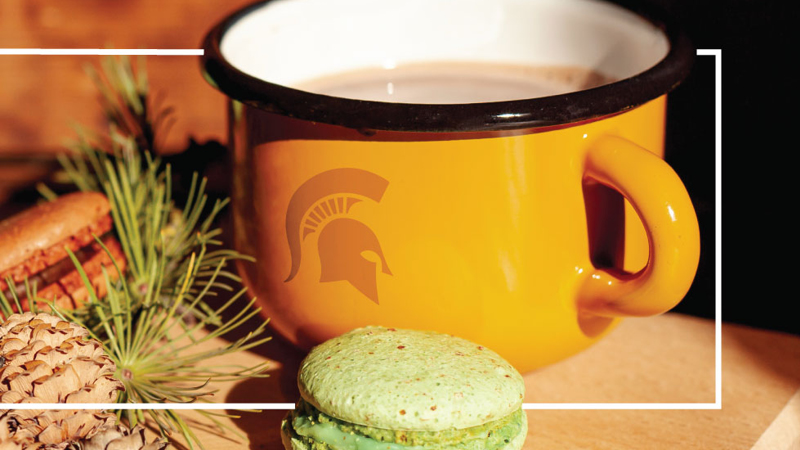 Cozy holiday scene with Spartan branded oversized coffee mug and green macarons.
