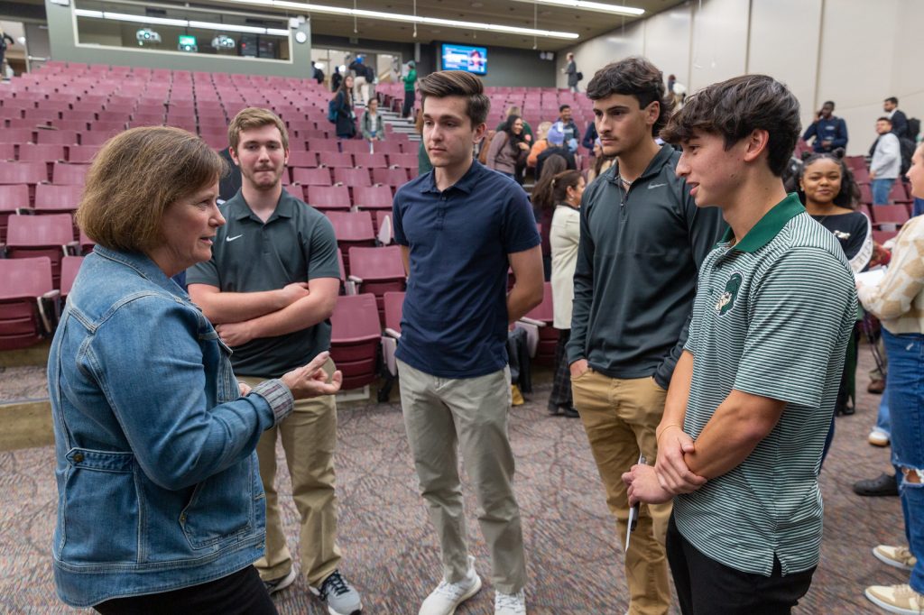 Linda Hubbard speaking with four Spartans at the end of the event.