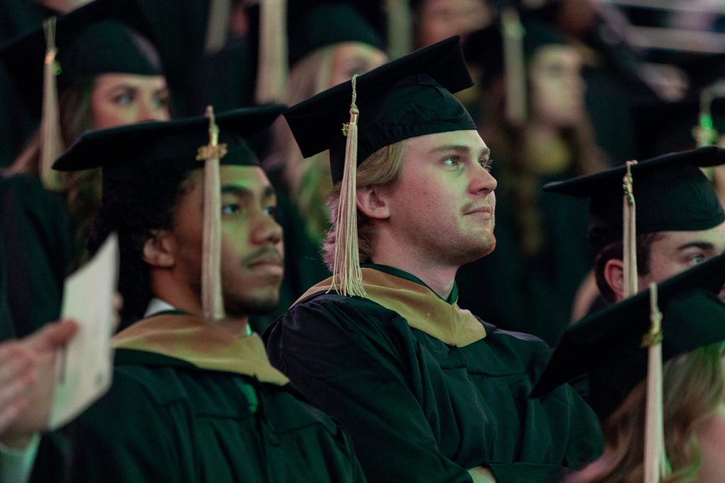 Broad Spartans gaze to the right, donned in master's regalia at the Breslin Center for commencement.