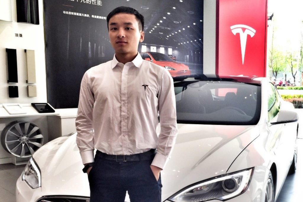 Yuan Lin standing in front of a Tesla car