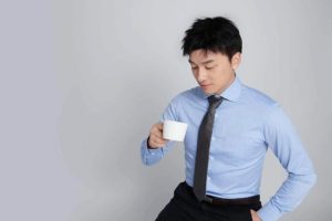 photo of Linc (Yuan Lin) wearing a blue shirt with a tie and holding a white coffee mug