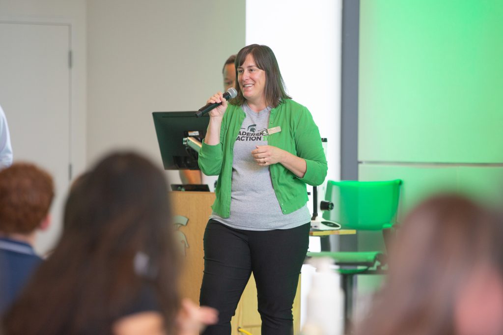 Beth Hammond holds a microphone while speaking at a college event.