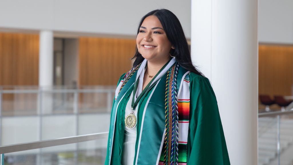 The 2024 Broad College commencement student speaker Diana Talamantes-Valles wearing academic regalia while walking in the Minskoff Pavilion.