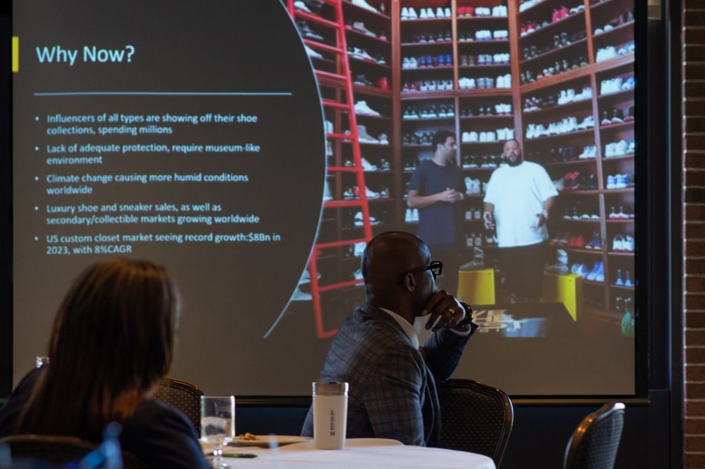 Audience members looking at a slide deck during a presentation at the 2024 EMBA Pitch Competition.