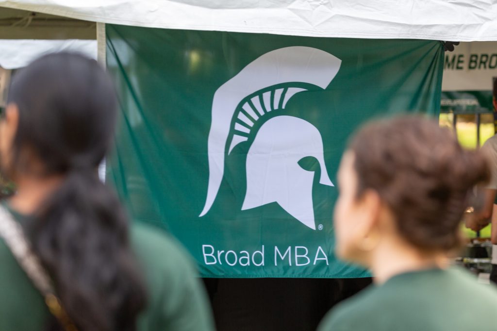 A large Broad MBA flag with Spartan helmet on display at a homecoming tailgate event on campus.