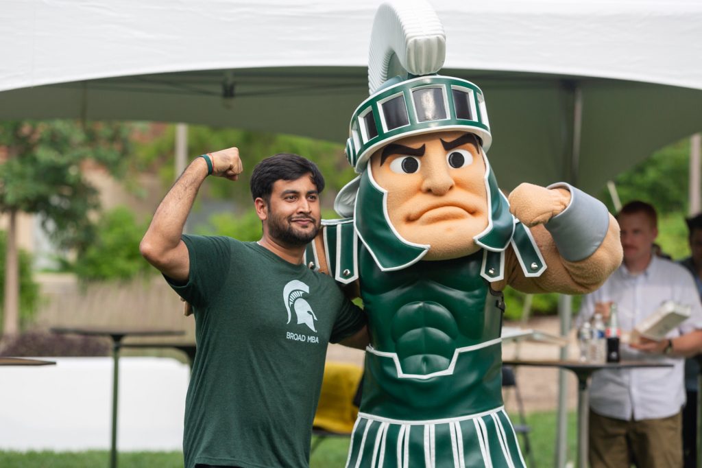 A Broad MBA student poses with Sparty at an outdoor event on campus.