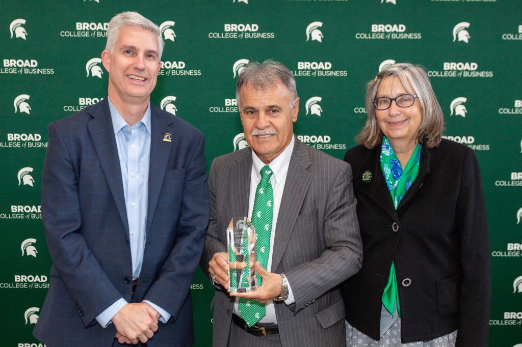 Alumni award winner standing with Broad College of Business Dean and guest