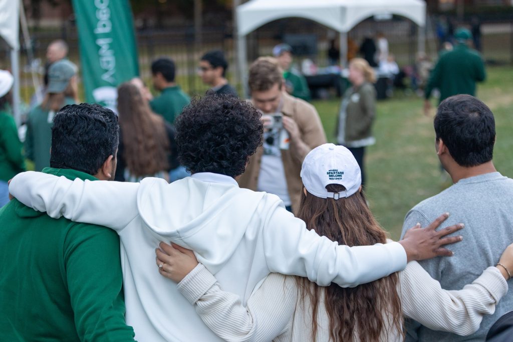 Students facing away taking a group photo at the MBA Homecoming Tailgate