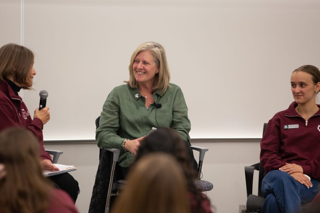 Three women sitting on a panel and speaking into a microphone