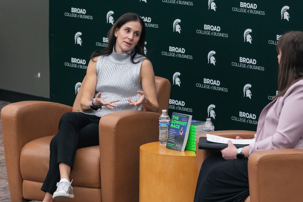 Kara Goucher sitting next to her book and speaking to moderator