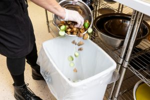 Person throwing away food in garbage can