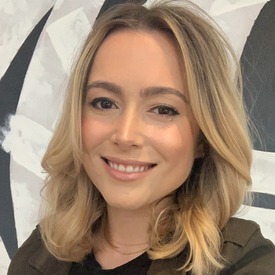 Headshot of woman smiling with blonde hair against a black and white background.