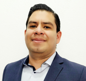 Headshot of a masculine presenting Latinx person in a collared shirt and suit jacket.