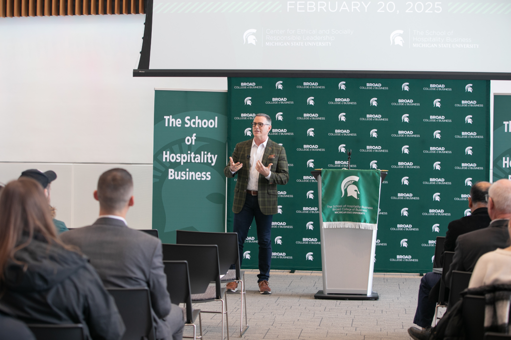 Person speaking at lecturn to a seated crowd