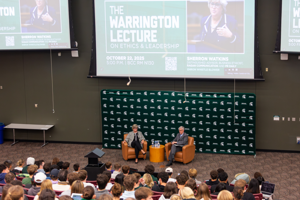 Two seated people in front of full auditorium