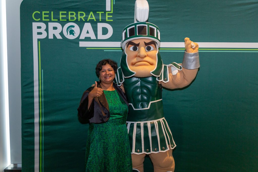 An award recipient gives a thumbs up while posing beside the Michigan State Spartan mascot in front of a “Celebrate Broad” backdrop.