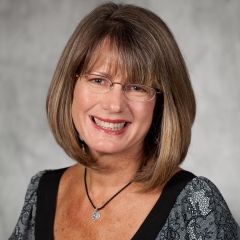 Penni Vandecar headshot - woman smiling in front of gray background