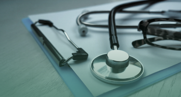Stethoscope, clipboard, eyeglasses, and reflex hammer arranged on a desk, representing healthcare management and medical practice.