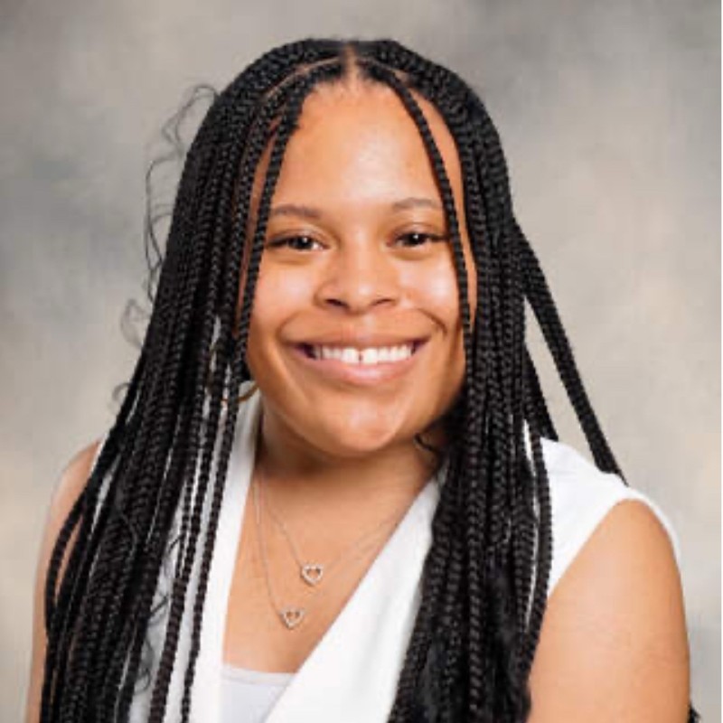 Woman with long dark braids in a white shirt smiling