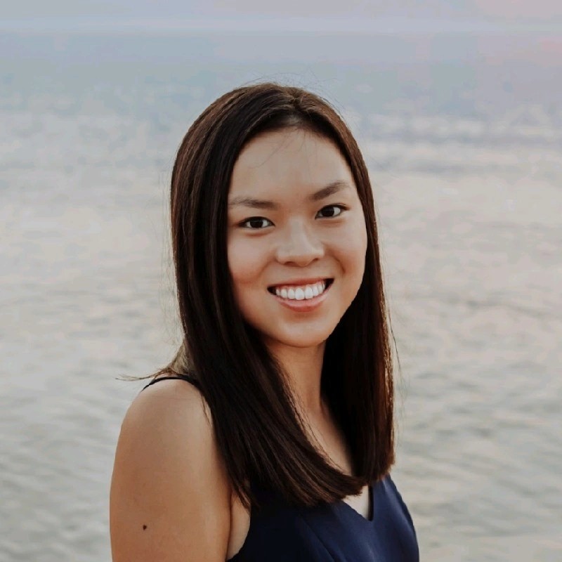 Woman in a dark top on a beach smiling