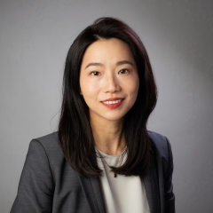 A professional headshot of Lu Zhang in a grey blazer with a white top.