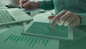 Professional analyzing financial charts on a tablet beside a laptop, highlighting skills taught in MSU’s Master’s in Financial Technology and ai