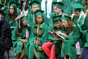 A group of Spartan graduates look through a program before the ceremony