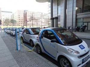 Electric cars lined up to charge along the side of a city street