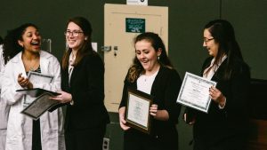 From left: Another participant claps as the first-place team of Victoria Zehner, Katlyn Ratzlaff, and Megan Mowid are honored.