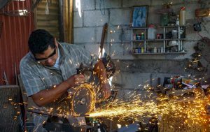 Carlos Diaz cutting metal to make a knife in his shop in Guatemala
