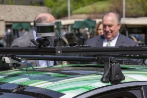 A sensor sits ready atop a driverless car while inspected by Michigan State University Interim President John Engler (background right) during an autonomous vehicle workshop hosted by MSU in mid-May. Photo by Zach Hall