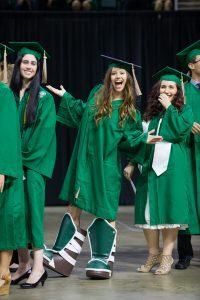 Nicole Niemiec (center) reveals herself as a Sparty mascot by wearing her mascot costume's footwear at Broad College of Business commencement ceremonies in May. Photo by Matthew Mitchell