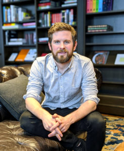 A high quality image of Jesse Juriga, MSU Broad Marketing alumnus and creative director at Google Creative Lab, sitting in a leather chair with a bookshelf behind him.