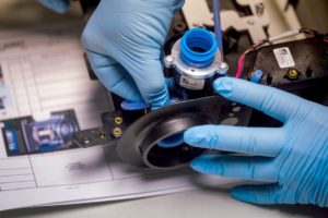 A close up image of a General Motors employee work on ventilator parts.