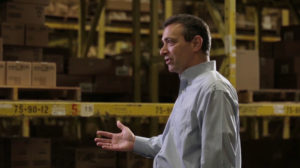 Dennis Eidson (B.A. Business Administration ’76), Chairman of the Board and interim President and CEO of SpartanNash, pictured speaking inside a warehouse. 