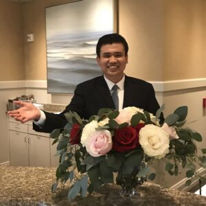 Vinh Le (B.A. Hospitality Business '21) dressed professional behind a front desk at a hotel.