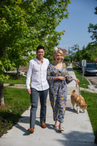 Hospitality business grads Kyle Welch and Alex Clark smile and walk their dog on a sunny day. Photo courtesy of Gerard + Belevender