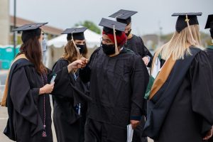 Broad Full-Time MBA graduates celebrate at commencement during pandemic wearing masks, caps and gowns.