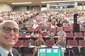 Faculty John Spink takes a selfie in front of filled lecture hall.