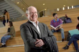 John Hollenbeck, Eli Broad Professor and University Distinguished Professor, standing in the Minskoff Pavilion atrium with students studying in the background.