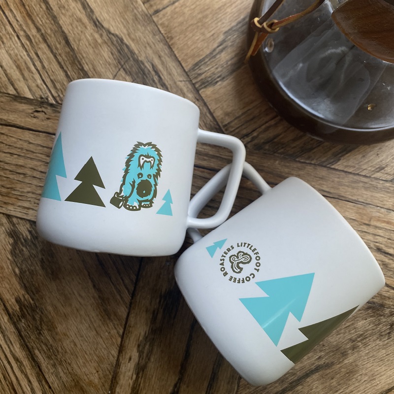 Coffee mugs with Littlefoot Coffee Roasters logo and branding.