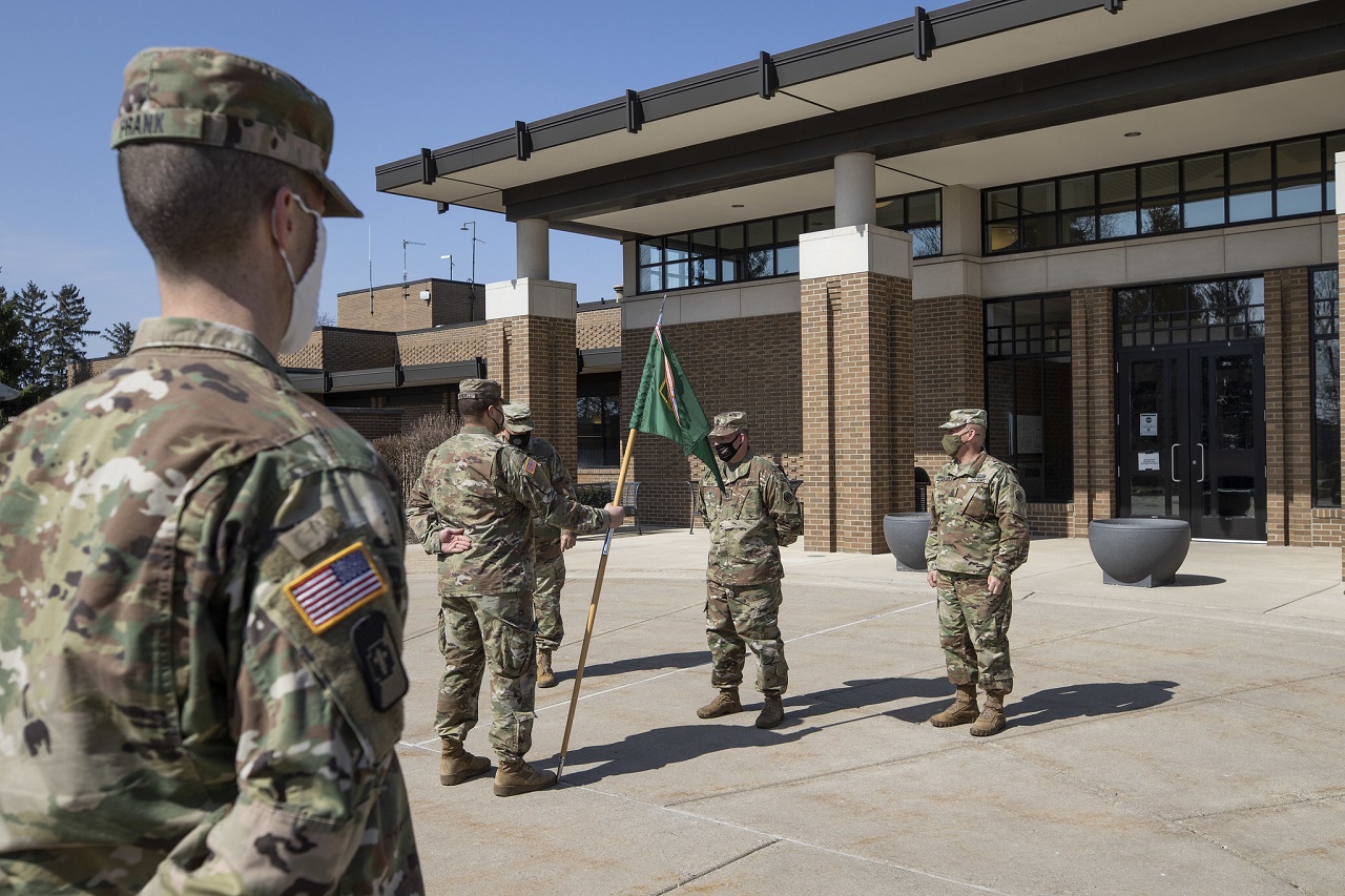 Military members of Task Force 46 stand in formation outside on a sunny day.