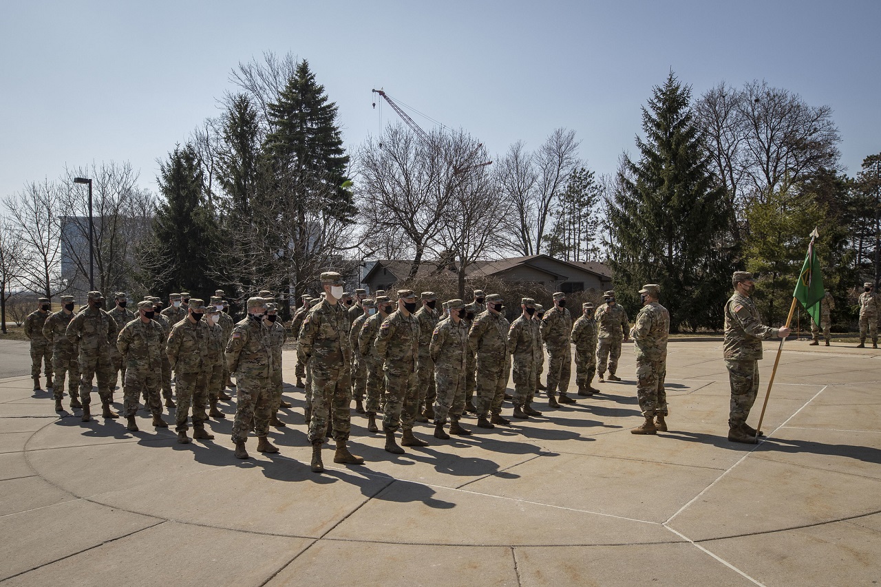 Military members of Task Force 46 stand in formation outside on a sunny day.